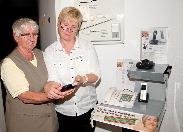 Zwei Frauen testen gemeinsam seniorenfreundliche Telefone mit großer Tastatur und Display.